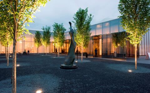 Exterior of West Building entrance and courtyard garden at night — North Carolina Museum of Art.